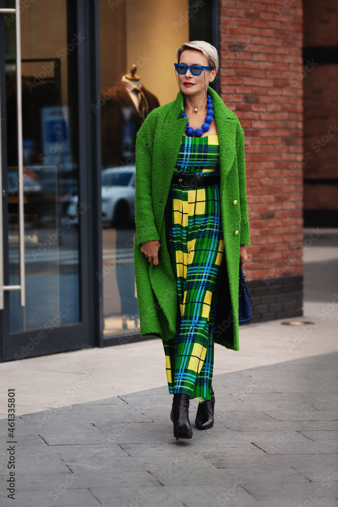 Full-length portrait of fashionable adult woman in long green coat and elegant dress. Fashion Trend For Fall or Spring. Stylish Woman outfit with blue accessories and sunglasses Full-length portrait of fashionable adult woman in long green coat and elegant dress. Fashion Trend For Fall or Spring. Stylish Woman outfit with blue accessories and sunglasses