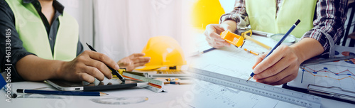 Two colleagues discussing data working and tablet, laptop with on on architectural project at construction site at desk in office