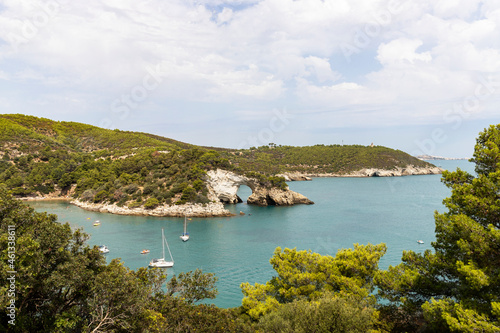 Arch of San Felice, Vieste. Gargano promontory with rocks in the sea, trees and vegetation, boats. Concept of vacation on the Gargano in Puglia, Italy.