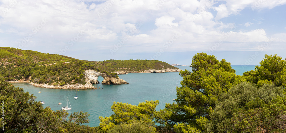 Naklejka premium Arch of San Felice, Vieste. Gargano promontory with rocks in the sea, trees and vegetation, boats. Concept of vacation on the Gargano in Puglia, Italy.