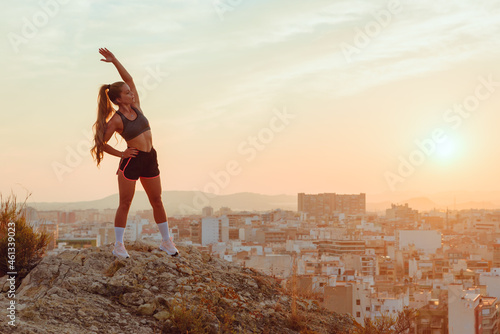pretty young woman does yoga overlooking the city at sunset outdoors