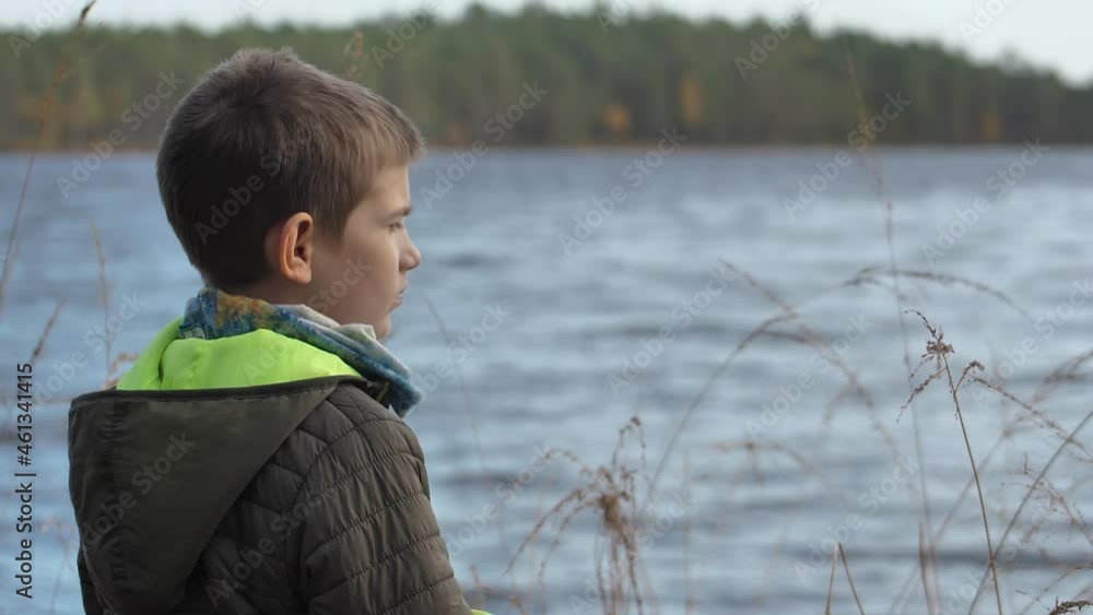 The child stands alone on the shore of the lake The child stands alone on the shore of the lake
