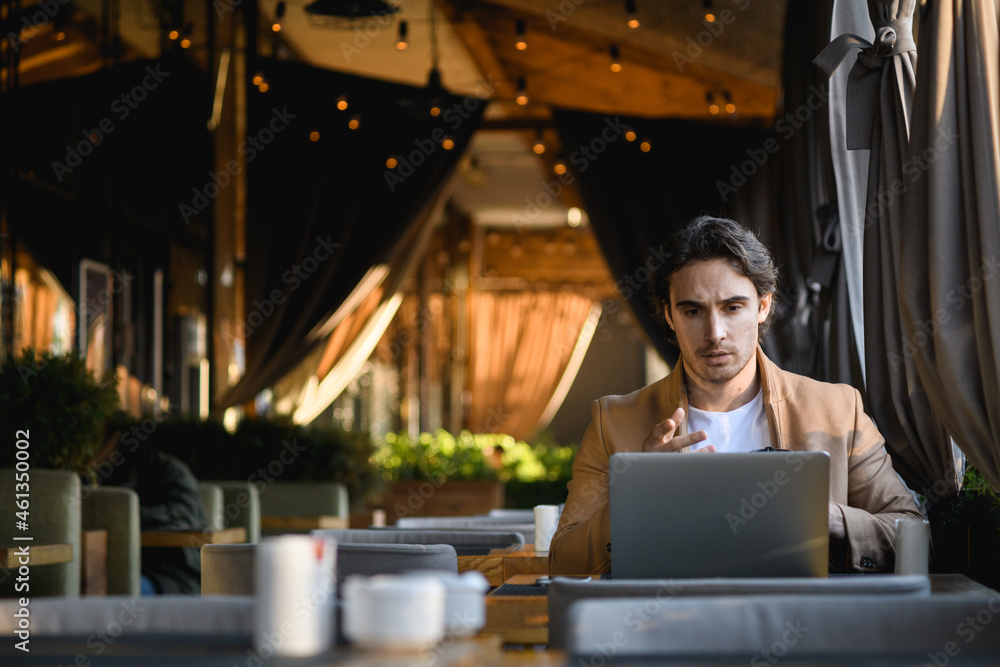 Businessman talking during video call on laptop on terrace of cafe Businessman talking during video call on laptop on terrace of cafe