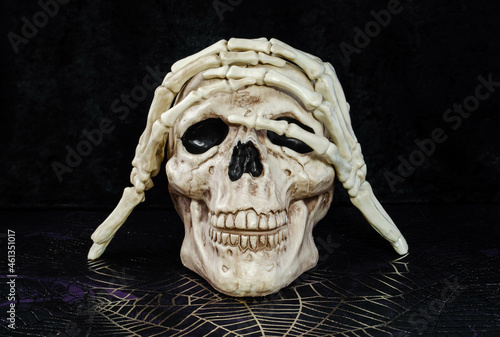 A skull halloween decoration and skeleton hands posing
