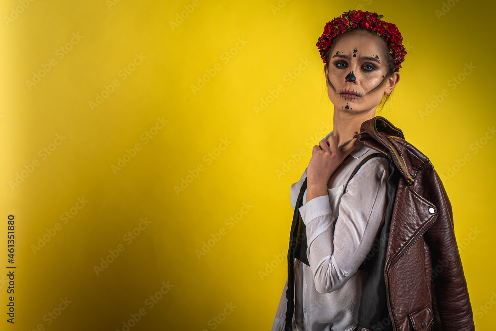 Close-up portrait of Kalavera Katrina close up in white shirt and brown leather jacket on yellow background, looks straight. Dia-de -los -muertos. Day of death. Halloween