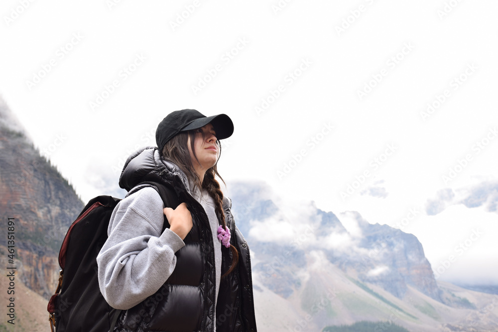 Young girl with backpack admiring the beauty of mountains on her hike