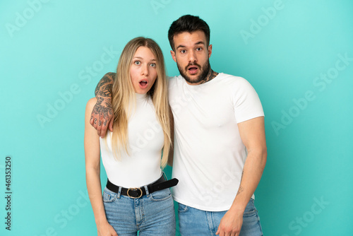 Young couple over isolated blue background with surprise facial expression