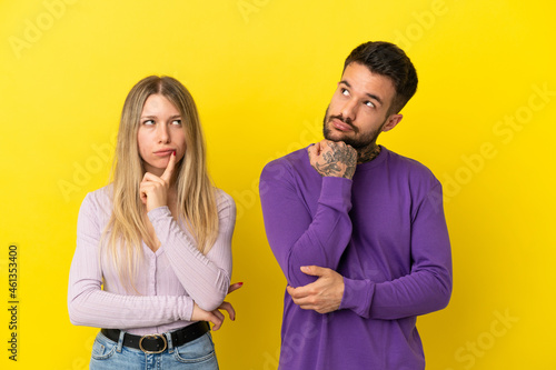 Young couple over isolated yellow background standing and thinking an idea