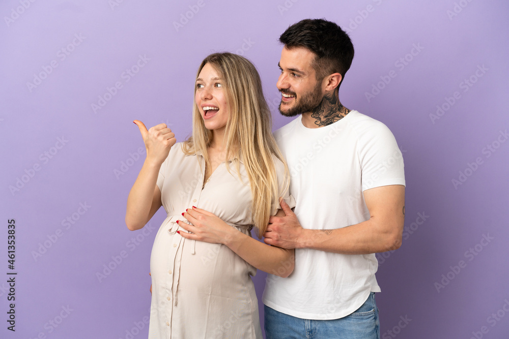Fototapeta premium Young couple pregnant and pointing to the lateral