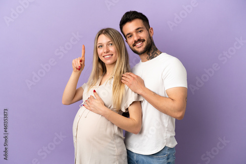 Young couple pregnant and pointing up