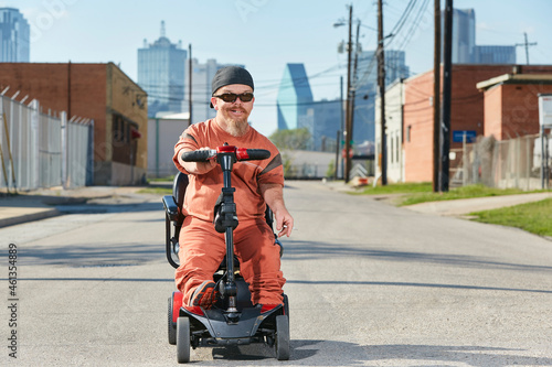 Portrait of male dwarf in the street in Texas riding a mobility scooter, smoking a cigarette photo