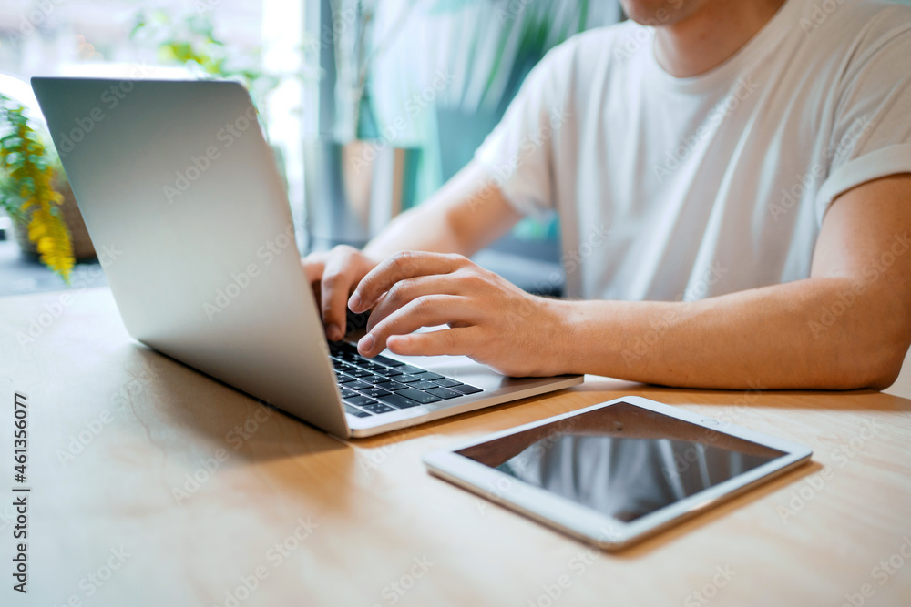 Fototapeta premium An employee counts finances in an online table. A man works in a cafe on a laptop. Writes an email to clients.
