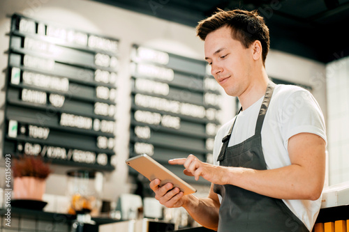 Sells drinks and food in cafes. An employee counts finances in an online table. An entrepreneur and his restaurant are a small business. A man works in a cafe on a laptop. photo