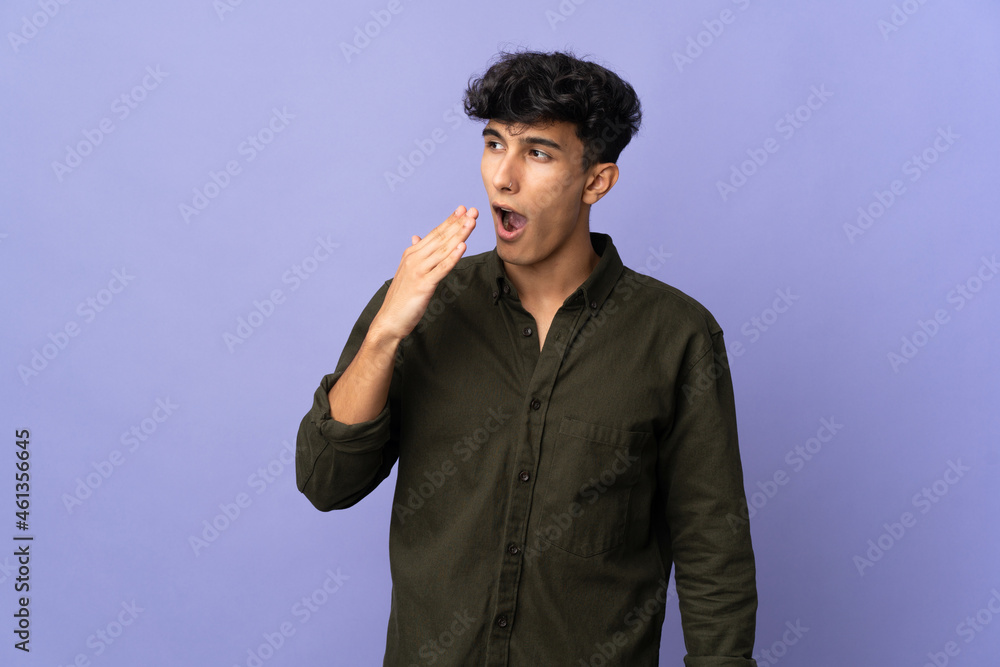 Young Argentinian man isolated on background yawning and covering wide open mouth with hand Young Argentinian man isolated on background yawning and covering wide open mouth with hand