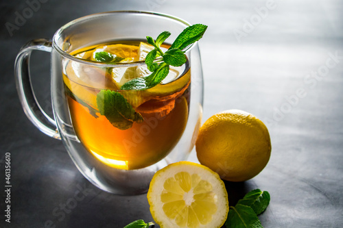 Tea with lemon and mint in transparent cup. Alternative medicine for treatment.