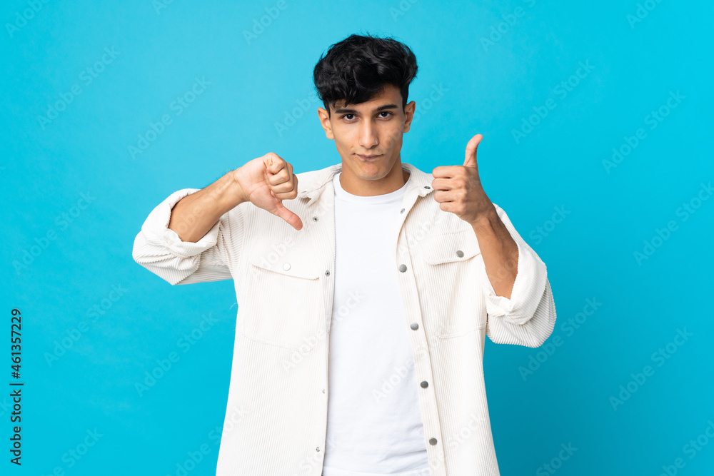 Young Argentinian man isolated on background making good-bad sign. Undecided between yes or not Young Argentinian man isolated on background making good-bad sign. Undecided between yes or not
