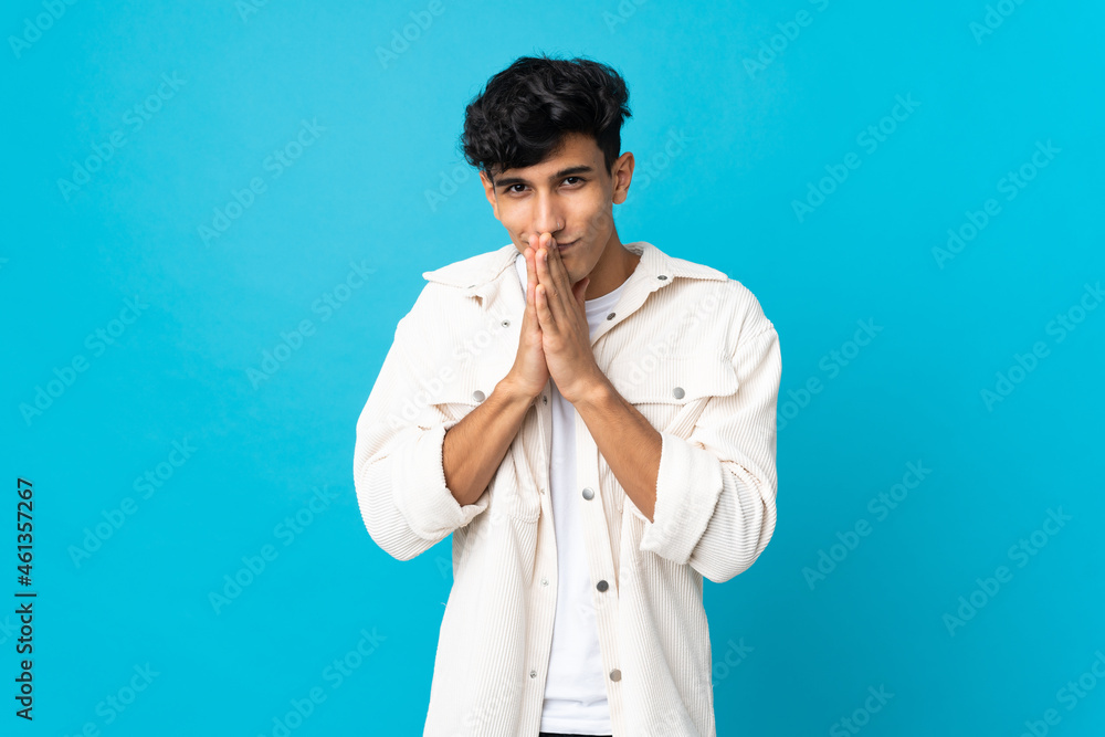 Fototapeta premium Young Argentinian man isolated on background keeps palm together. Person asks for something