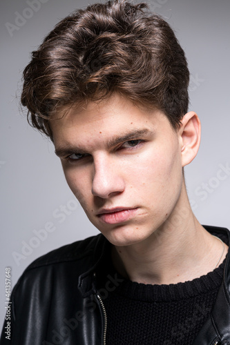 Wide angle portrait Young male model in black clothes posing in studio white background. Guy wearing black classic leather jacket. Handsome young fashion model man portrait. Attractive guy