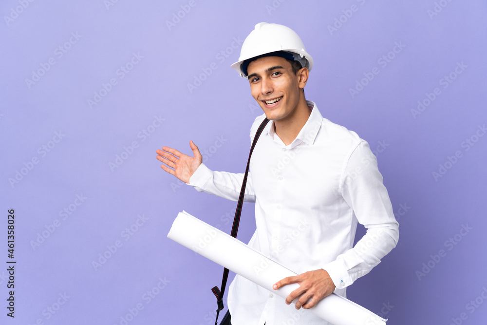 Young architect man isolated on background extending hands to the side for inviting to come Young architect man isolated on background extending hands to the side for inviting to come