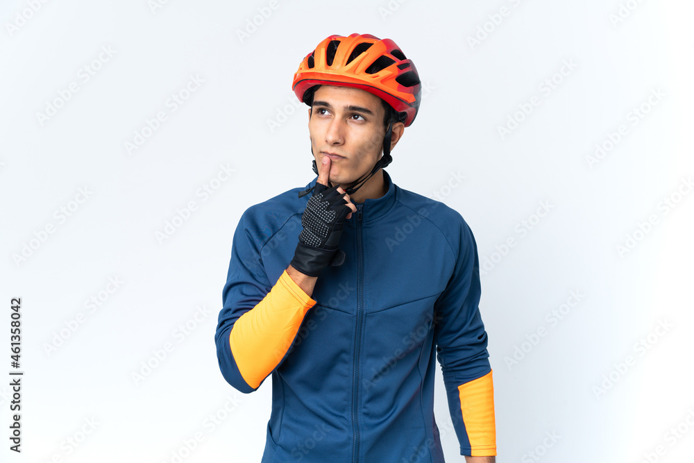Young cyclist man isolated on background having doubts while looking up Young cyclist man isolated on background having doubts while looking up