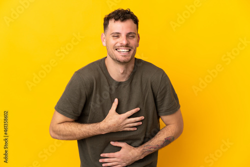 Young caucasian handsome man isolated on yellow background smiling a lot