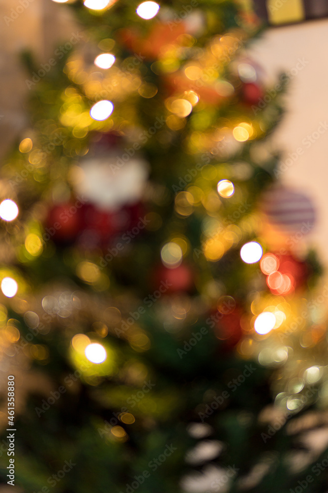 Blurred Christmas tree assembled with ornaments. Red, silver and gold balls, gift boxes, lights, Santa Claus and others. To insert something in front in focus.