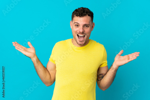 Young caucasian handsome man isolated on blue background with shocked facial expression