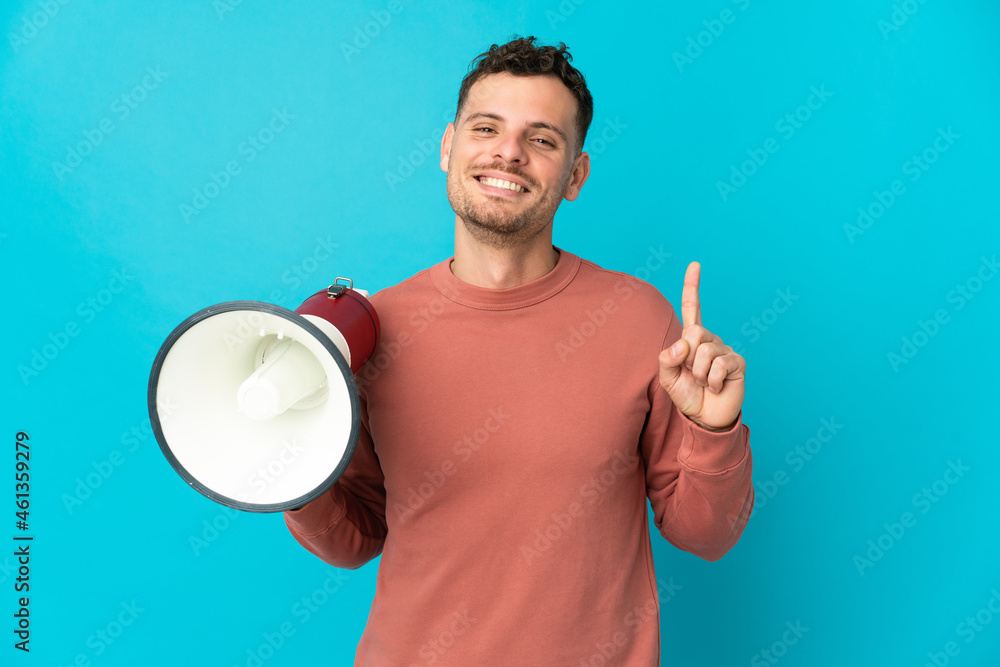 Young caucasian handsome man isolated on blue background holding a megaphone and pointing up a great idea Young caucasian handsome man isolated on blue background holding a megaphone and pointing up a great idea
