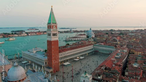 Aerial drone video of famous Saint Mark's square or Piazza San Marco with Basilica, Campanile and Adriatic Sea. Establishing Shot of Venice Cityscape, Italy. 4K Zoom in shot