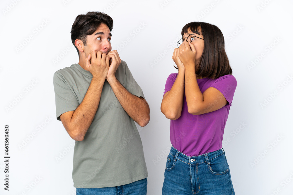 Young couple isolated on isolated white background is a little bit nervous and scared putting hands to mouth Young couple isolated on isolated white background is a little bit nervous and scared putting hands to mouth