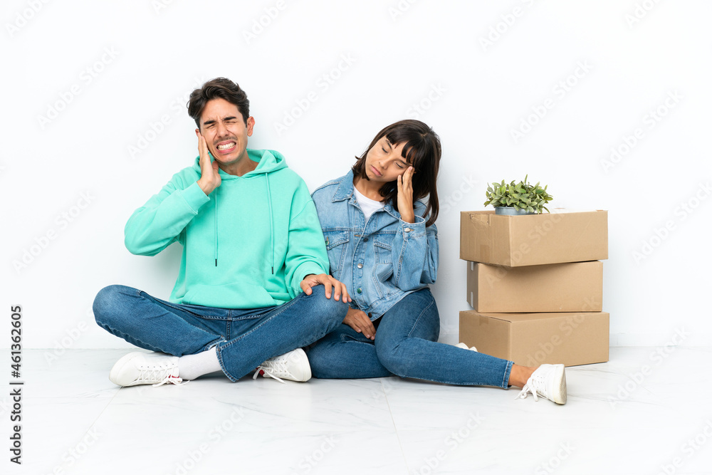 Young couple making a move while picking up a box full of things sitting on the floor isolated on white background unhappy and frustrated with something Young couple making a move while picking up a box full of things sitting on the floor isolated on white background unhappy and frustrated with something