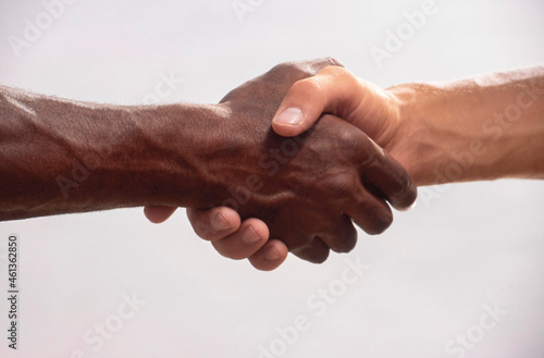 Close up of male black hand and white hand shaking photo