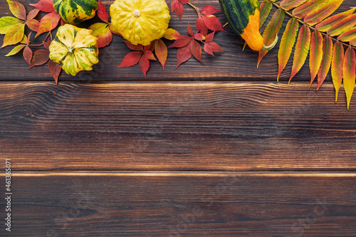 Autumn background with pumpkins and colorful leaves on a dark wooden table. Happy Thanksgiving concept. Flat lay, copy space