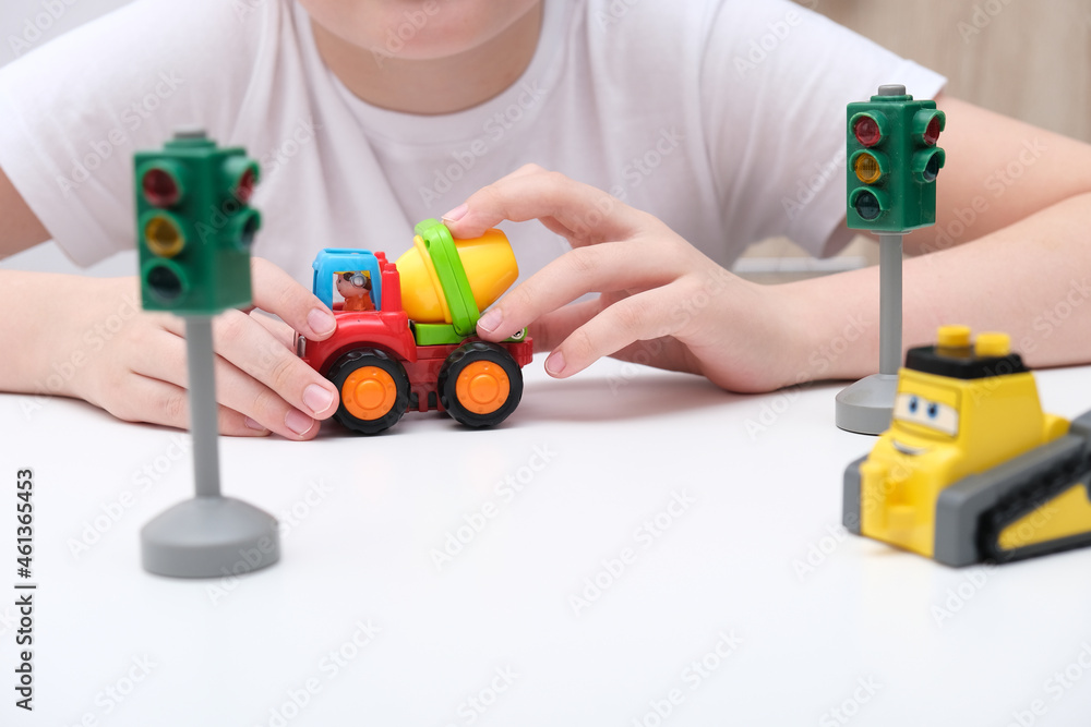 Fototapeta premium An unrecognizable boy playing toy cars and traffic lights, learning traffic rules in playful way