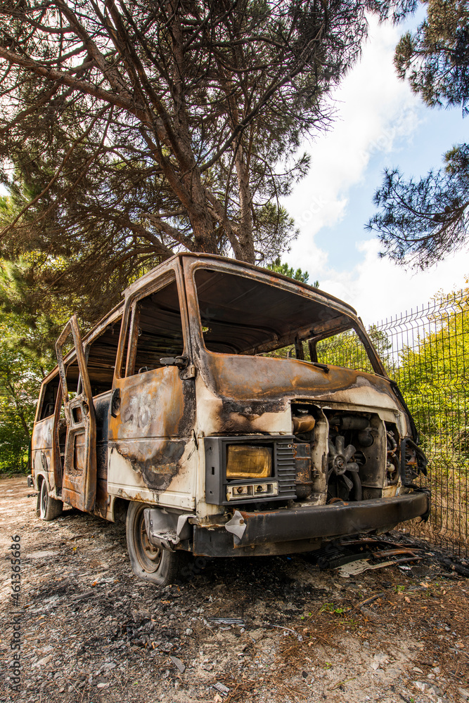 Abandoned burning van next to a forest totally wrecked