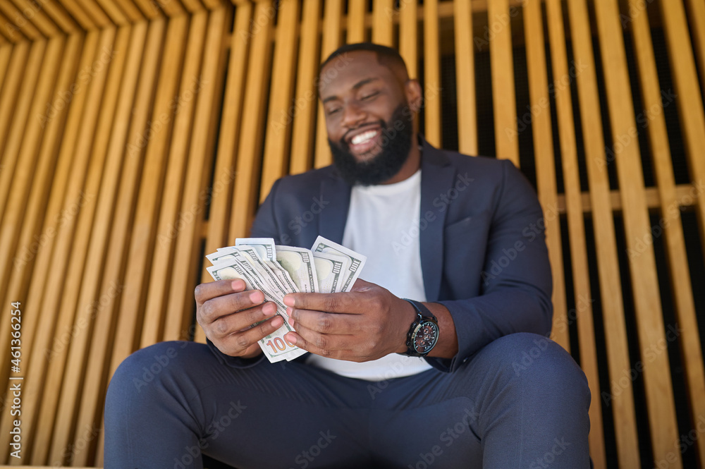 Obraz premium A man sitting on the bench and holding dollars in hands