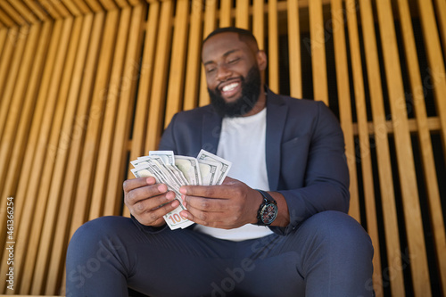 Konstfotografi A man sitting on the bench and holding dollars in hands