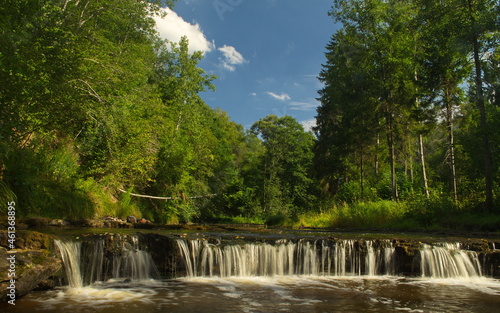 Small river with woods, rocks and waterfall.