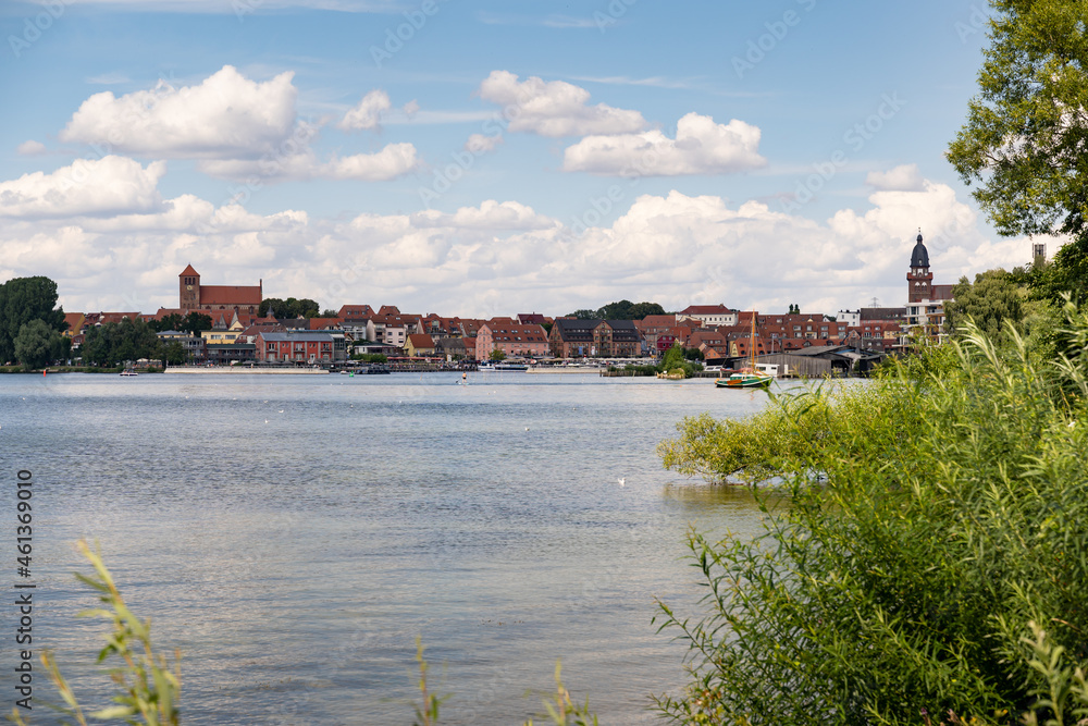 Waren city next to the lake. The harbor side is visible. The towers of the city are in the skyline of the town. Old architecture is in the landscape.