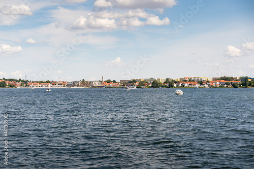 Waren city next to the lake. Old and new buildings are in the landscape. Boats are in the water in front of the town. Holidays during the summer in Germany.