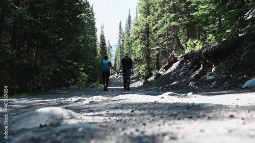 Couple walking down hiking path holding hands in Colorado forest, static low angle photo