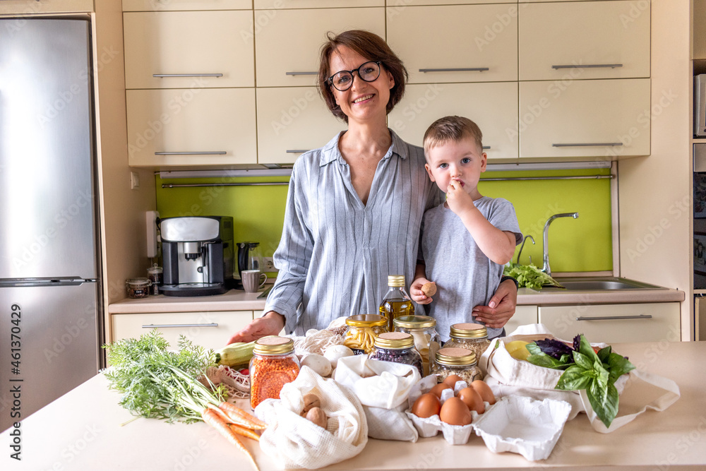 Adult mother feeds her son with nuts in the kitchen. Zero waste concept. Adult mother feeds her son with nuts in the kitchen. Zero waste concept.