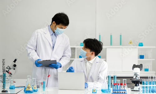 Two scientists with face mask discuss about blood samples of patients infected with Coronavirus disease 2019. Healthcare and medical concept.