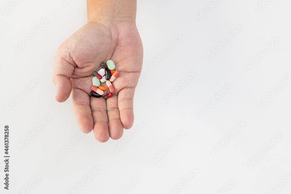 A man holding pill in hands taking emergency medicine, supplements or antibiotic antidepressant and painkiller medication to relieve pain.Medical side effects concept on white table.Close up view. A man holding pill in hands taking emergency medicine, supplements or antibiotic antidepressant and painkiller medication to relieve pain.Medical side effects concept on white table.Close up view.