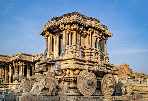 Richly sculpted stone chariot with clear blue sky background in Hampi, Karnataka.
