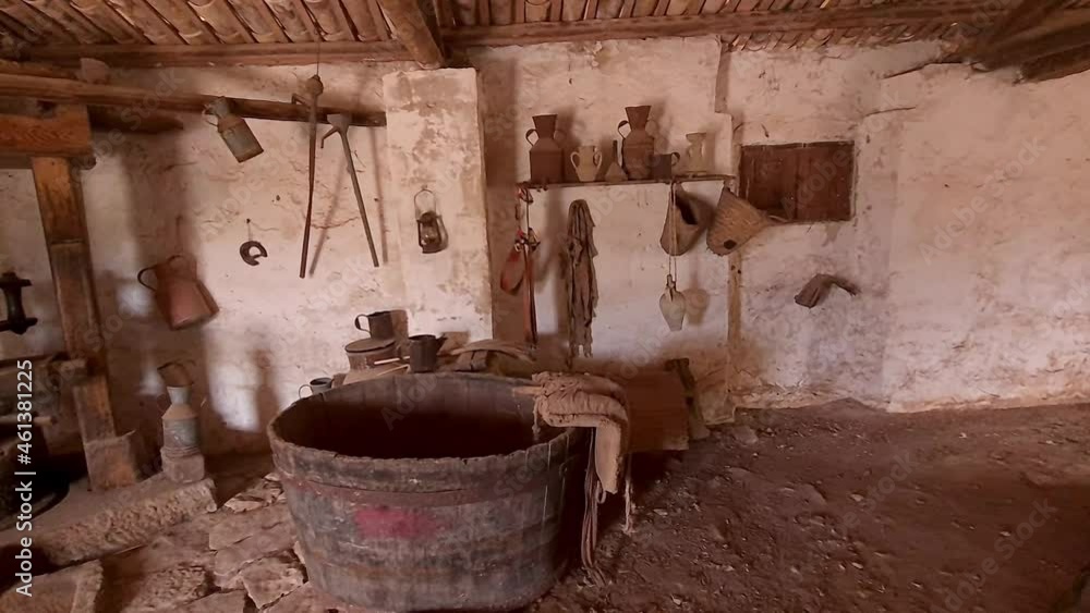 Interior of rural room with old millstone pulled by cows or horses and utensils hanging on wall at Grotta Mangiapane in Sicily, Italy. Panning Interior of rural room with old millstone pulled by cows or horses and utensils hanging on wall at Grotta Mangiapane in Sicily, Italy. Panning
