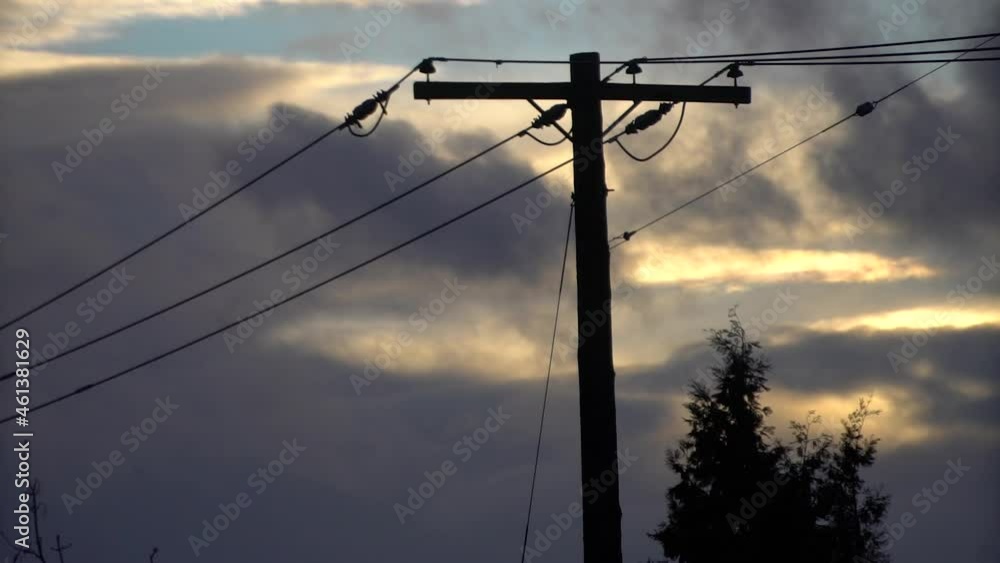 Static still of a silhouetted powerline during sunset on a partly cloudy day while birds fly in the background Static still of a silhouetted powerline during sunset on a partly cloudy day while birds fly in the background