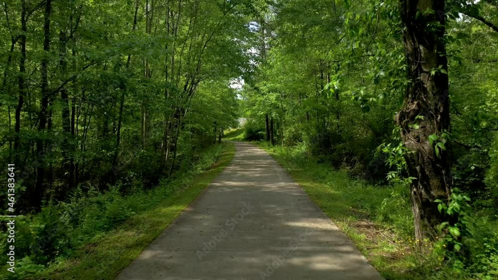 Drone shot going through a wooded area on a paved walking path in North Georgia Drone shot going through a wooded area on a paved walking path in North Georgia