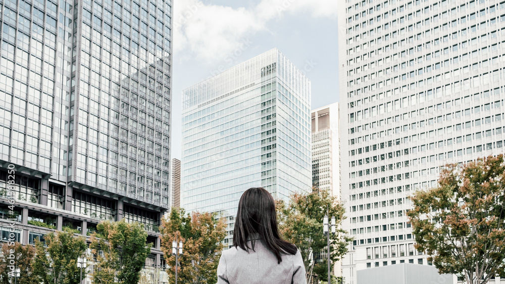 Fototapeta premium オフィス街にいるスーツ姿の女性（ビジネスイメージ）