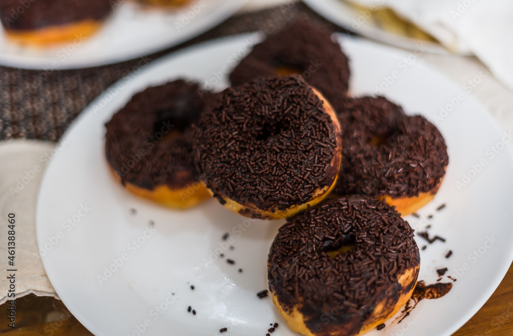 A stack of chocolate donut on white plate A stack of chocolate donut on white plate